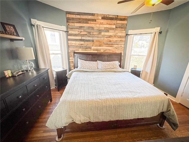 bedroom with wooden walls, dark wood-type flooring, and ceiling fan