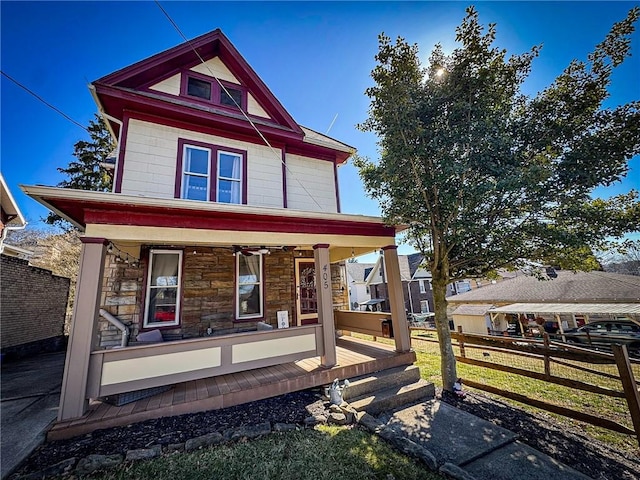 view of front of home with a porch, fence, and stone siding