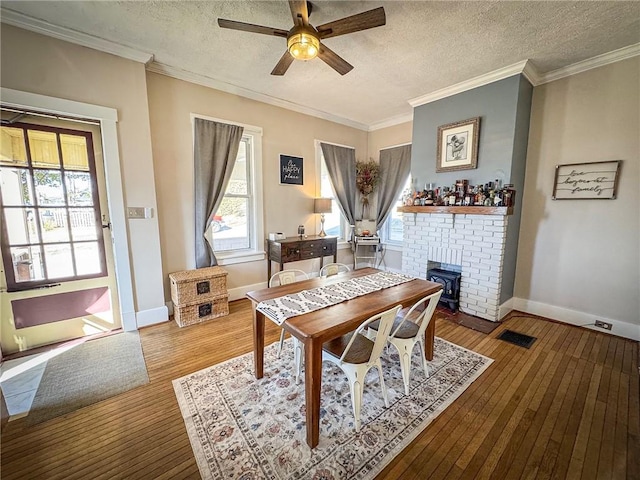 dining space with baseboards, visible vents, ornamental molding, wood-type flooring, and a textured ceiling