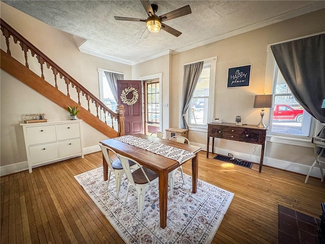 dining space with stairway, a textured ceiling, light wood-type flooring, and baseboards