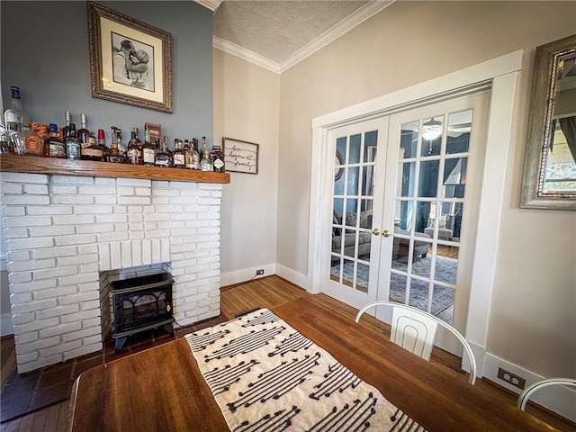 interior space featuring a textured ceiling, wood finished floors, french doors, crown molding, and baseboards