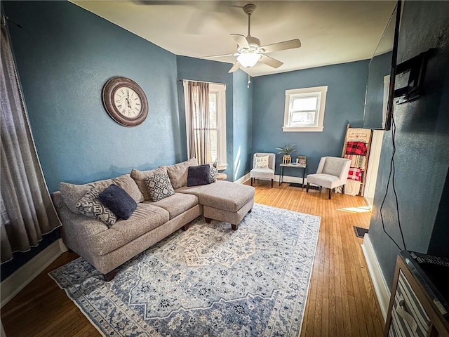 living room featuring baseboards, wood finished floors, and a ceiling fan