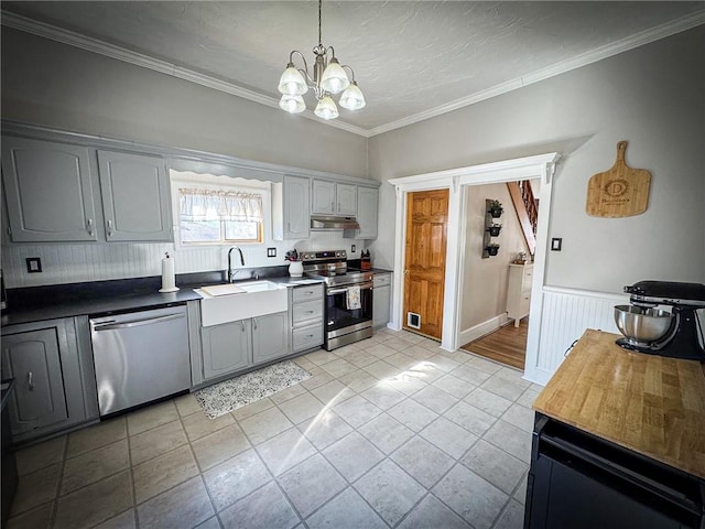 kitchen featuring a sink, under cabinet range hood, stainless steel appliances, an inviting chandelier, and crown molding