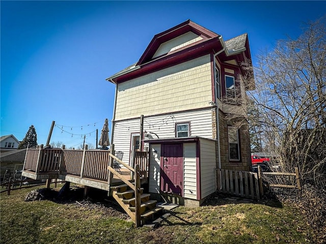 rear view of house with a deck, an outdoor structure, a storage unit, and a yard