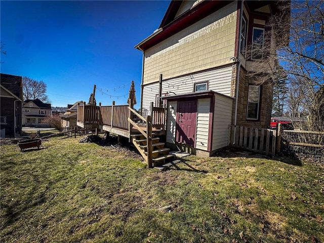 back of property featuring a yard, a deck, and fence