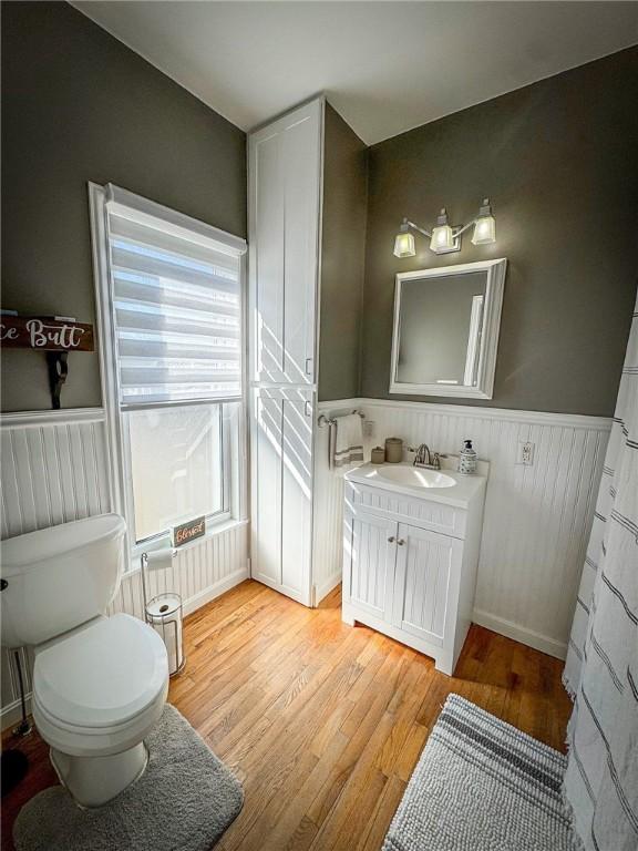 bathroom featuring a wainscoted wall, toilet, vanity, and wood finished floors