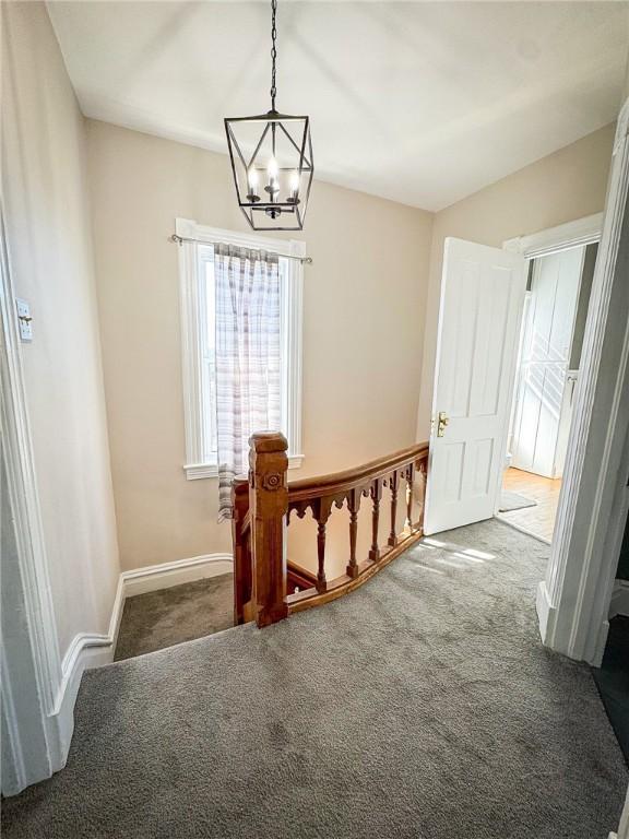 interior space with an inviting chandelier, baseboards, and carpet