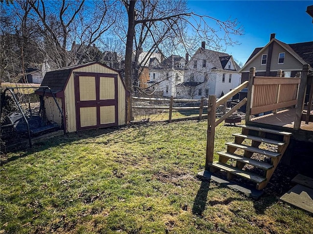 view of yard with a deck, a storage shed, an outdoor structure, and fence