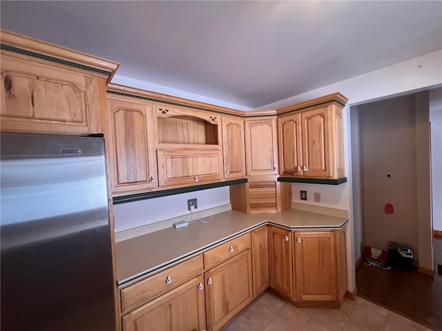 kitchen featuring light tile patterned flooring, built in desk, stainless steel fridge, and open shelves