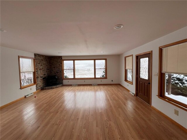 unfurnished living room with light wood-style flooring, baseboards, visible vents, and a large fireplace