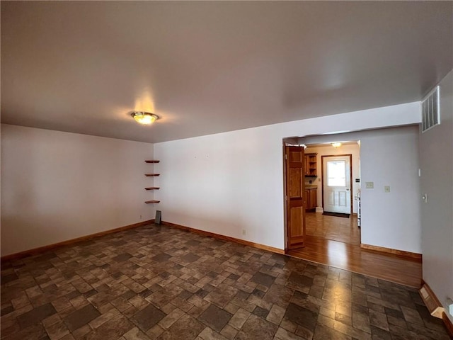 spare room with stone finish flooring, baseboards, and visible vents