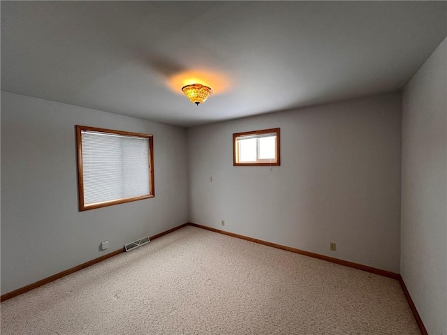 unfurnished room featuring baseboards, visible vents, and light carpet