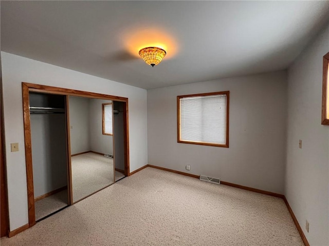 unfurnished bedroom featuring visible vents, baseboards, a closet, and light carpet