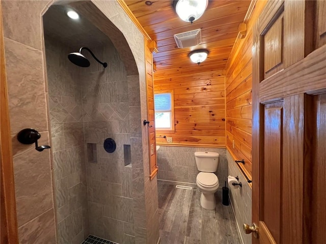 full bath with a tile shower, wooden ceiling, toilet, and wood finished floors