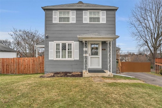 view of front facade with driveway, a front lawn, and fence