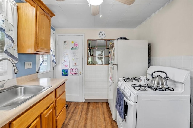 kitchen with light wood finished floors, light countertops, gas range gas stove, and a sink