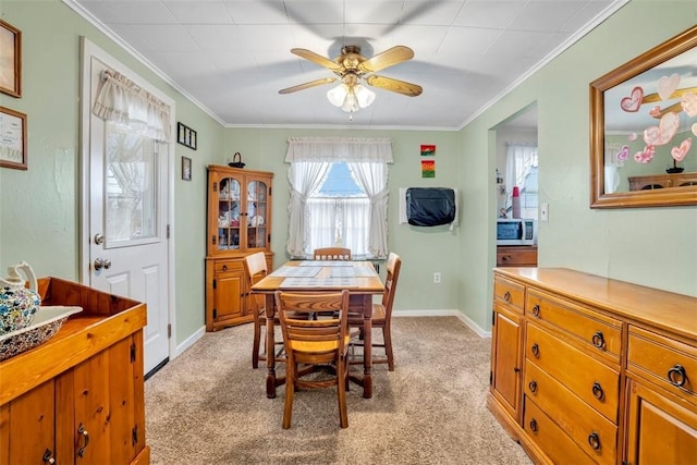 dining space featuring crown molding, light colored carpet, and baseboards