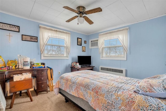 carpeted bedroom featuring a ceiling fan, a wall unit AC, radiator, and crown molding