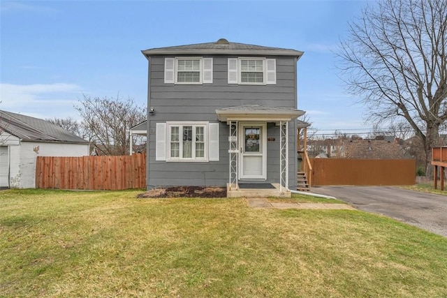 view of front facade featuring driveway, a front lawn, and fence