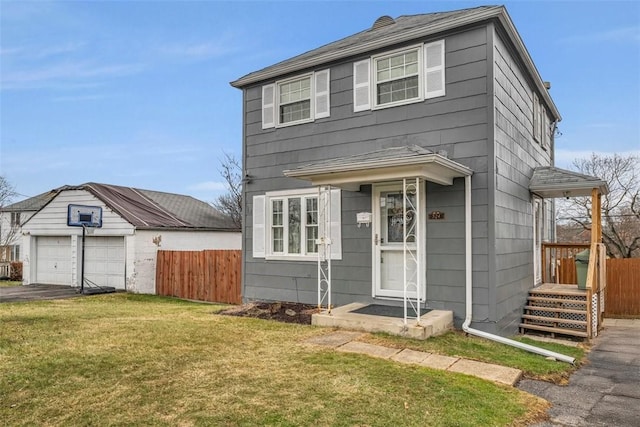 view of front of house featuring a detached garage, an outdoor structure, a front yard, and fence