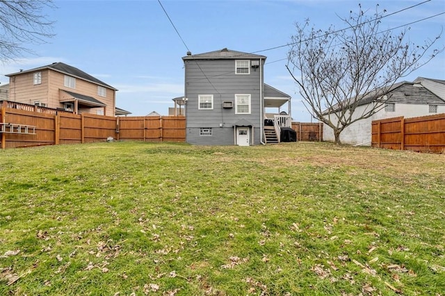 rear view of property featuring a lawn and a fenced backyard