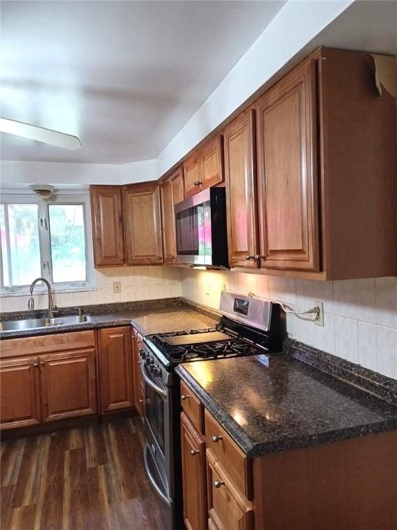 kitchen with tasteful backsplash, dark wood finished floors, brown cabinetry, stainless steel appliances, and a sink