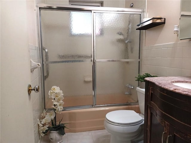 full bath with toilet, tile walls, tile patterned flooring, enclosed tub / shower combo, and vanity