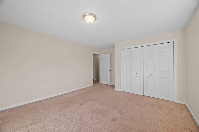 unfurnished bedroom featuring a closet, baseboards, and carpet flooring