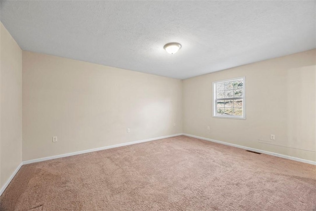 empty room with baseboards, visible vents, carpet floors, and a textured ceiling