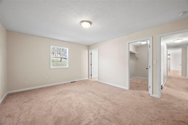 unfurnished bedroom featuring a spacious closet, baseboards, and carpet floors