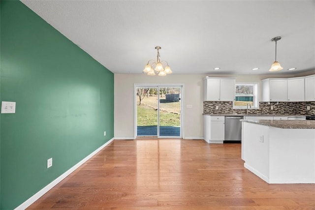 kitchen featuring baseboards, white cabinetry, light wood finished floors, stainless steel dishwasher, and tasteful backsplash