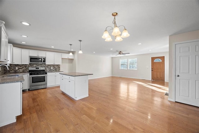 kitchen featuring dark countertops, light wood finished floors, appliances with stainless steel finishes, and a sink