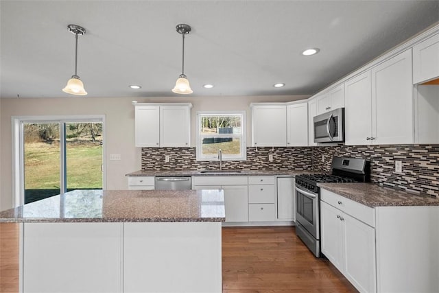 kitchen with a sink, tasteful backsplash, dark wood finished floors, stainless steel appliances, and white cabinets