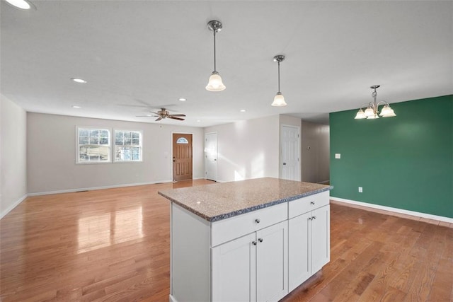 kitchen with baseboards, light wood finished floors, white cabinets, pendant lighting, and a center island