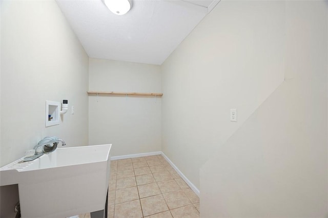 clothes washing area featuring washer hookup, a sink, light tile patterned floors, baseboards, and laundry area