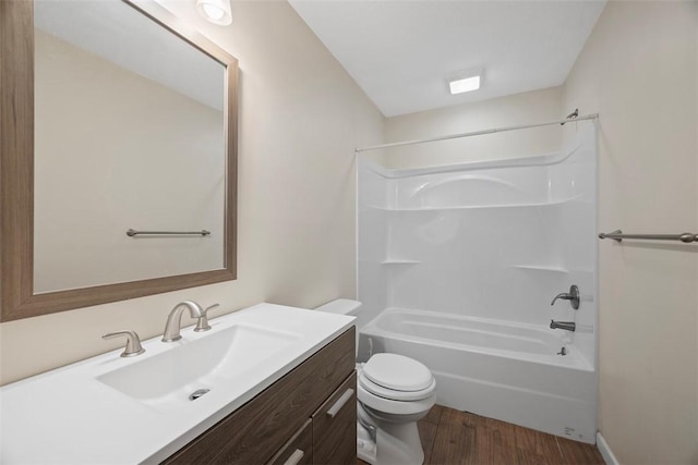 bathroom with vanity, washtub / shower combination, toilet, and wood finished floors