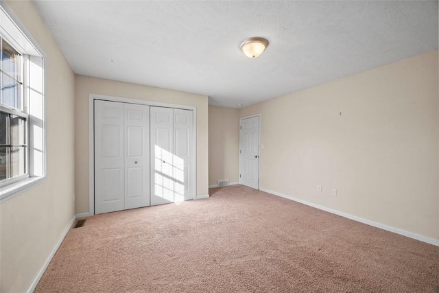 unfurnished bedroom featuring a closet, visible vents, baseboards, and carpet floors