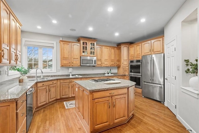 kitchen featuring a sink, light wood-style flooring, light stone countertops, and stainless steel appliances