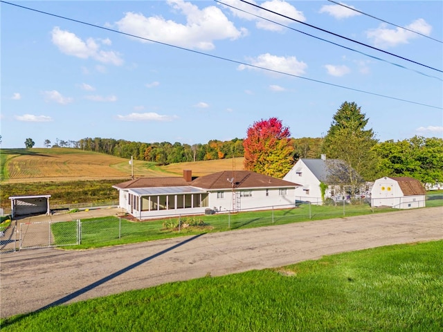 view of front of house featuring a gate, fence, a front lawn, and a sunroom