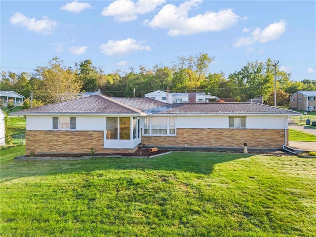 rear view of house featuring brick siding and a yard