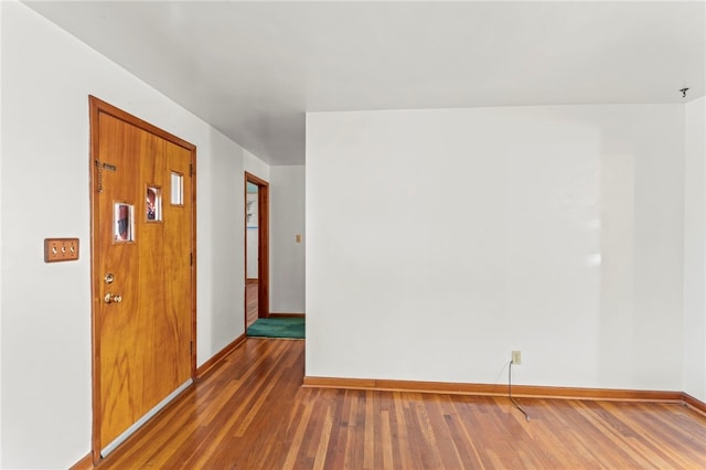 spare room featuring baseboards and wood finished floors