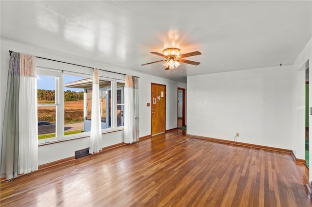 spare room featuring ceiling fan, visible vents, baseboards, and wood finished floors