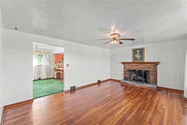 unfurnished living room with baseboards, wood finished floors, and a fireplace