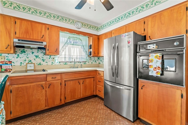 kitchen featuring black appliances, brown cabinets, under cabinet range hood, and a sink