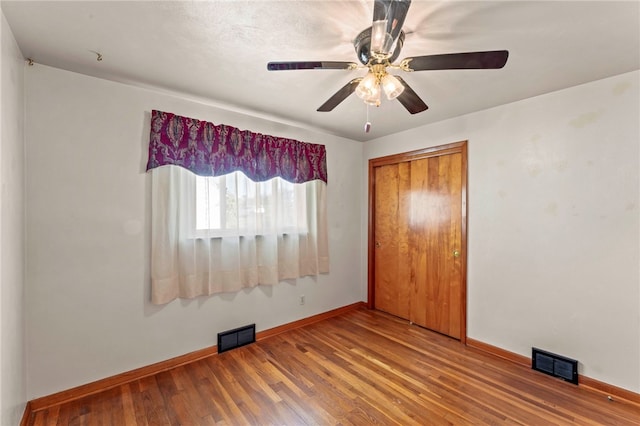 unfurnished bedroom with visible vents, baseboards, a closet, and wood finished floors