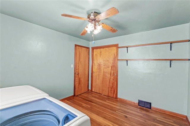 interior space with visible vents, a ceiling fan, washer / clothes dryer, wood finished floors, and laundry area