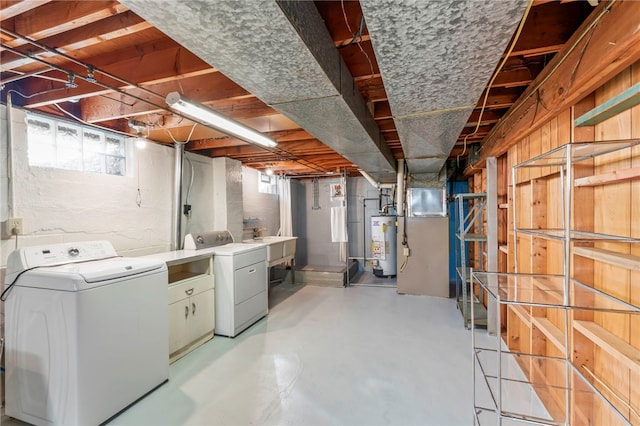 basement featuring a sink, heating unit, water heater, and washing machine and clothes dryer