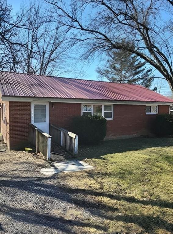 view of home's exterior featuring metal roof, a lawn, and brick siding