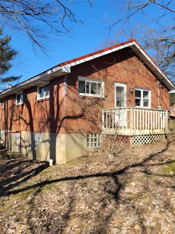 rear view of property featuring brick siding and a deck