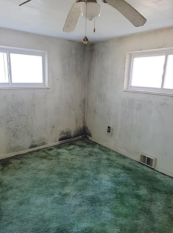 carpeted spare room featuring visible vents and ceiling fan